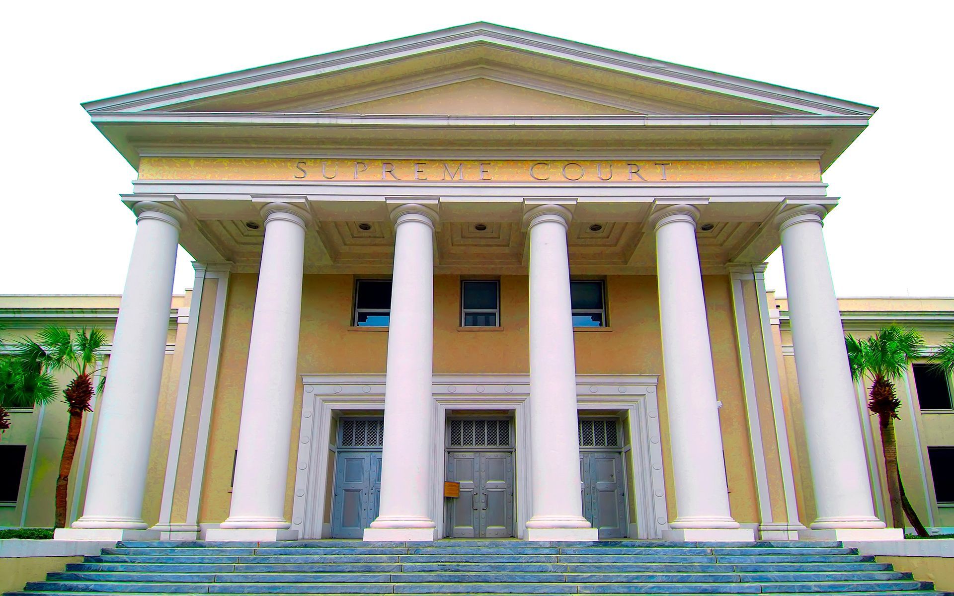 Courthouse with white columns, light yellow walls, and a symmetrical facade.  Exterior shot.