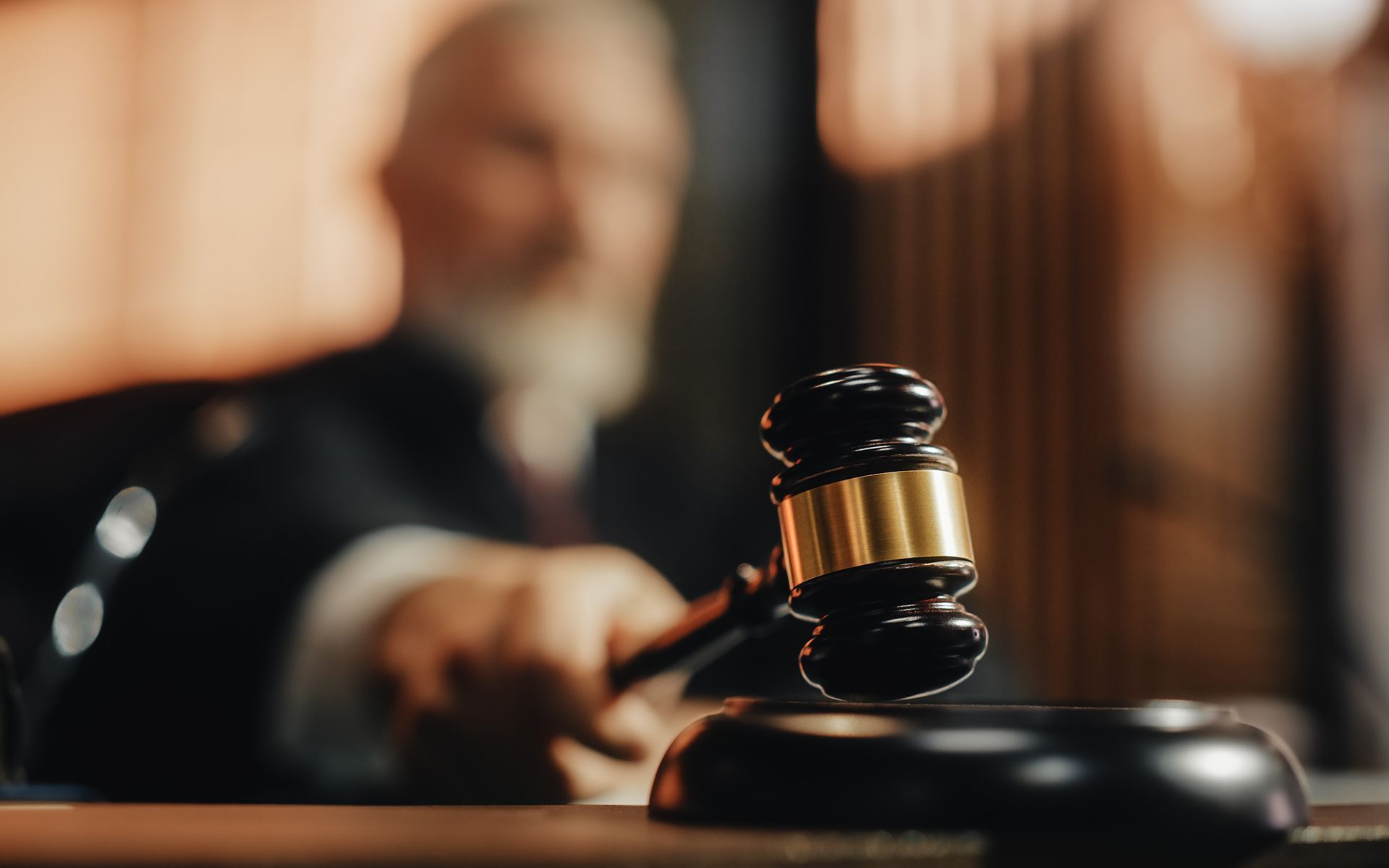 Judge holding a gavel, about to strike, in a courtroom setting.