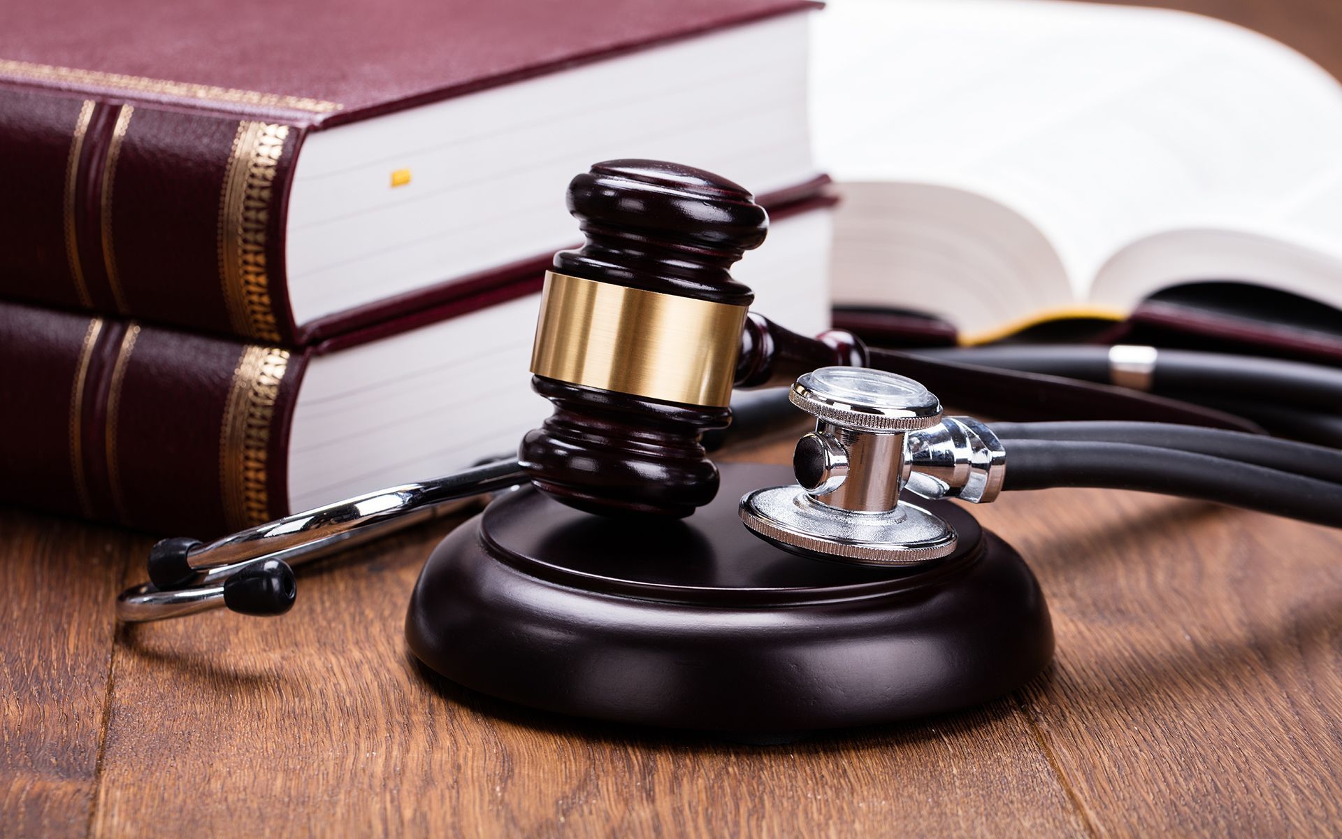 Gavel and stethoscope on wooden desk with law books, symbolizing medical law.