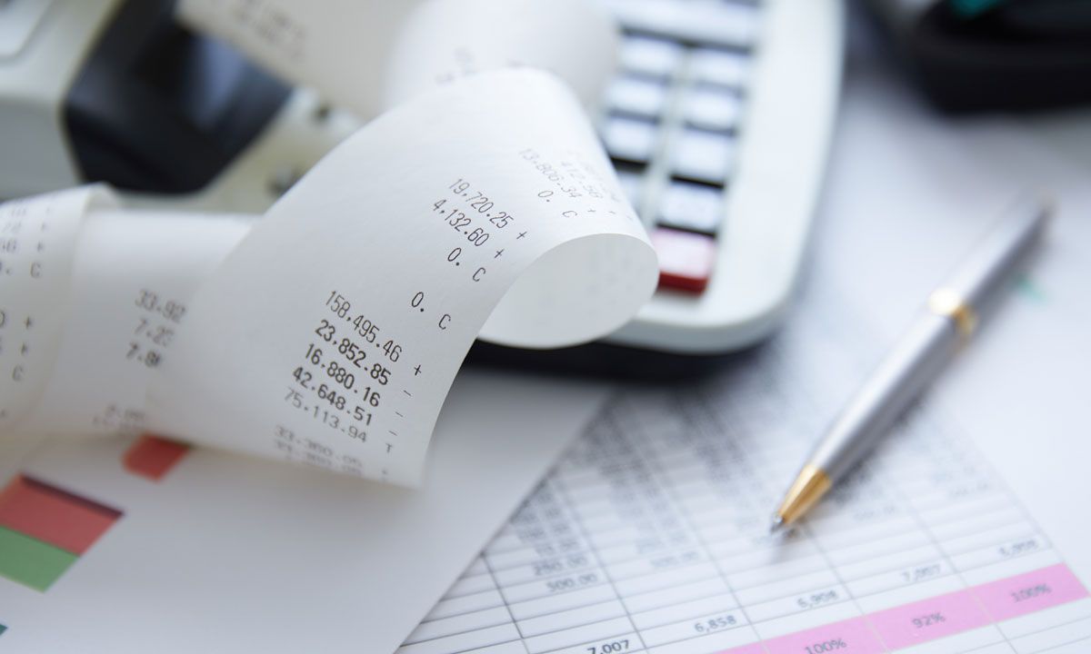 A receipt is laying on a table next to a pen and calculator.