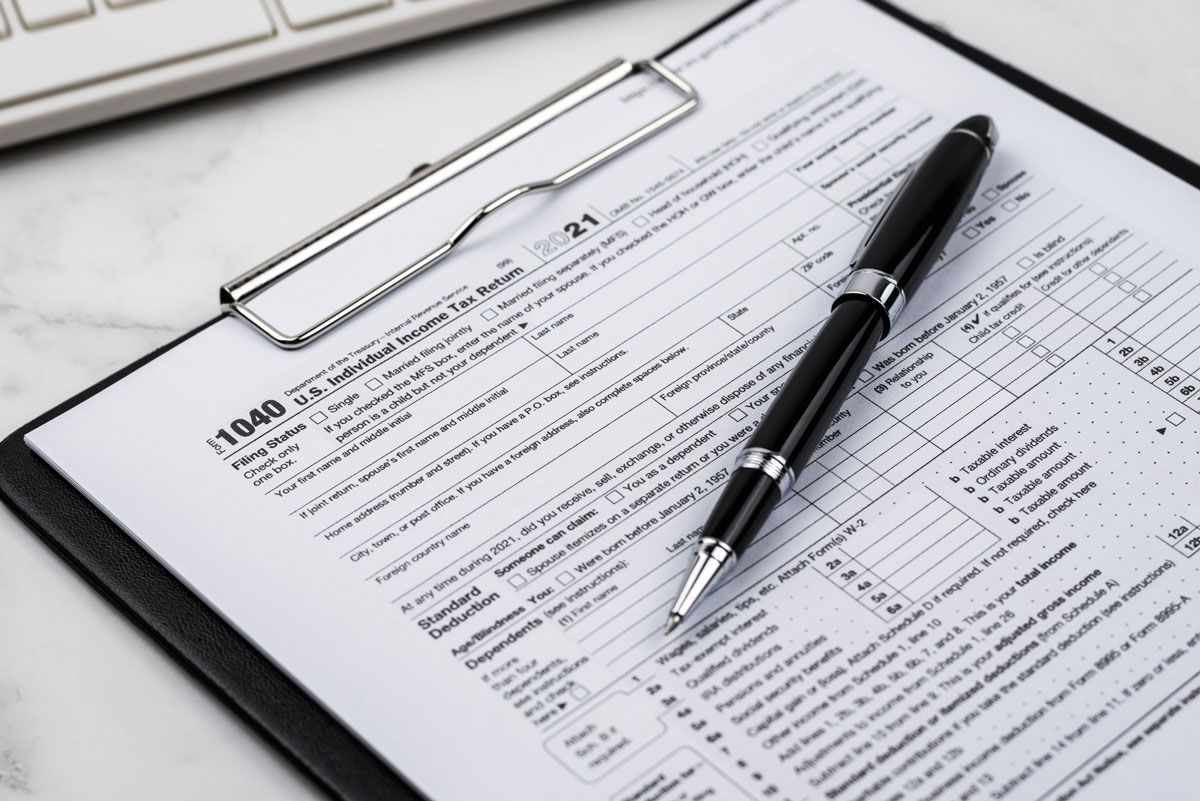 A pen is sitting on top of a clipboard with a tax form on it.