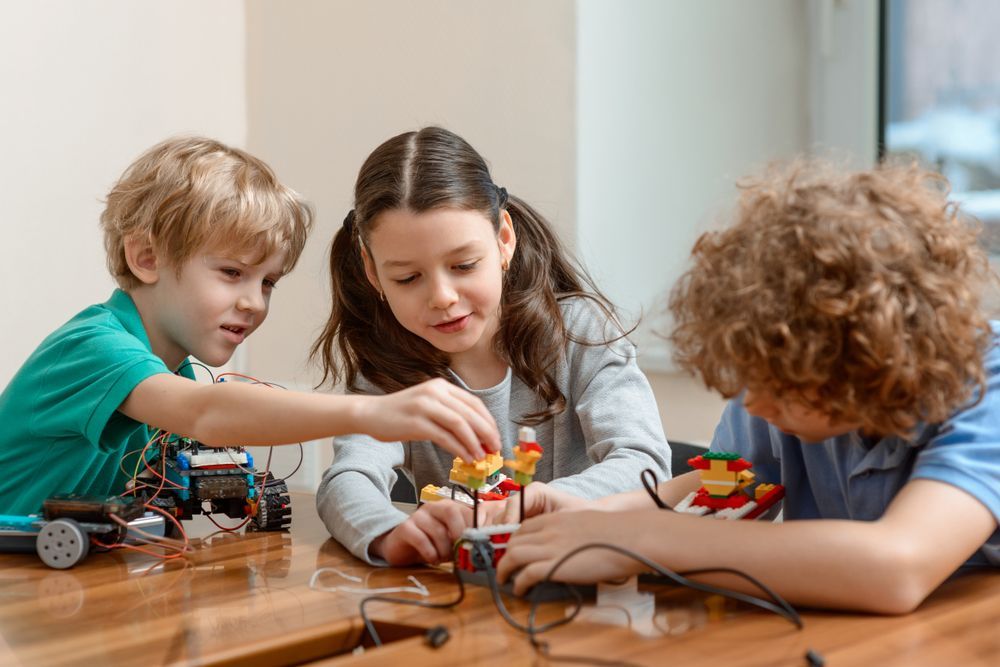 A Group of Children Are Sitting at a Table Playing With Lego — Specialist Support Solutions in Yeppoon, QLD
