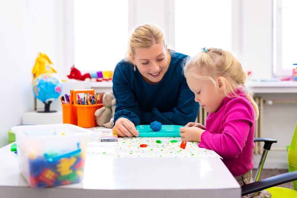 A Woman is Playing With a Little Girl at a Table — Specialist Support Solutions in Yeppoon, QLD