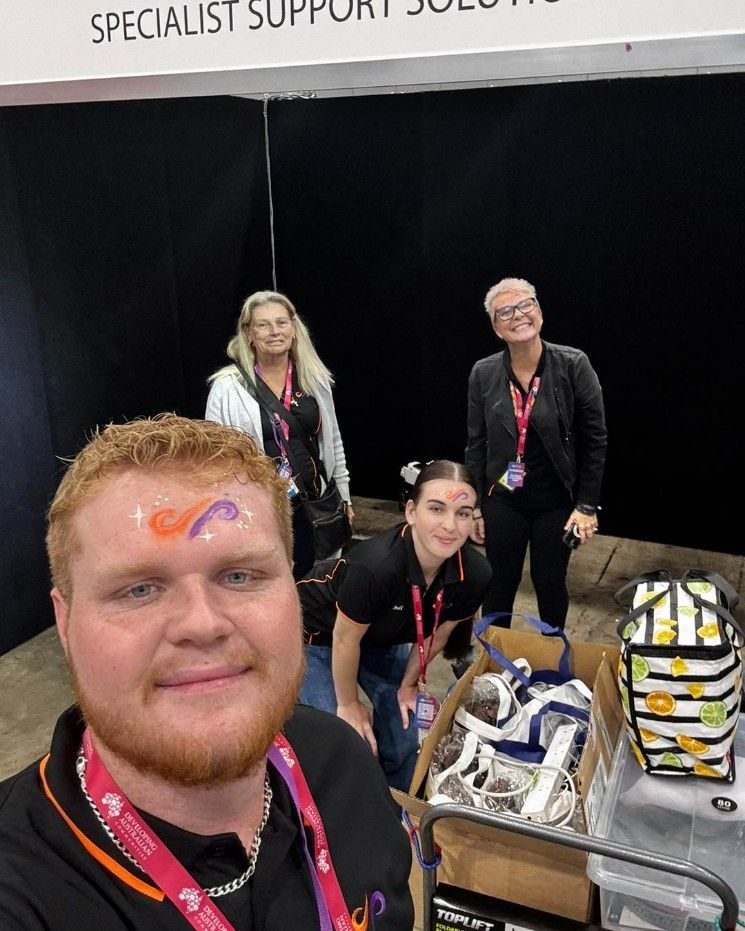 A Group of People Are Posing for a Selfie in Front of a Sign — Specialist Support Solutions in Gladstone, QLD