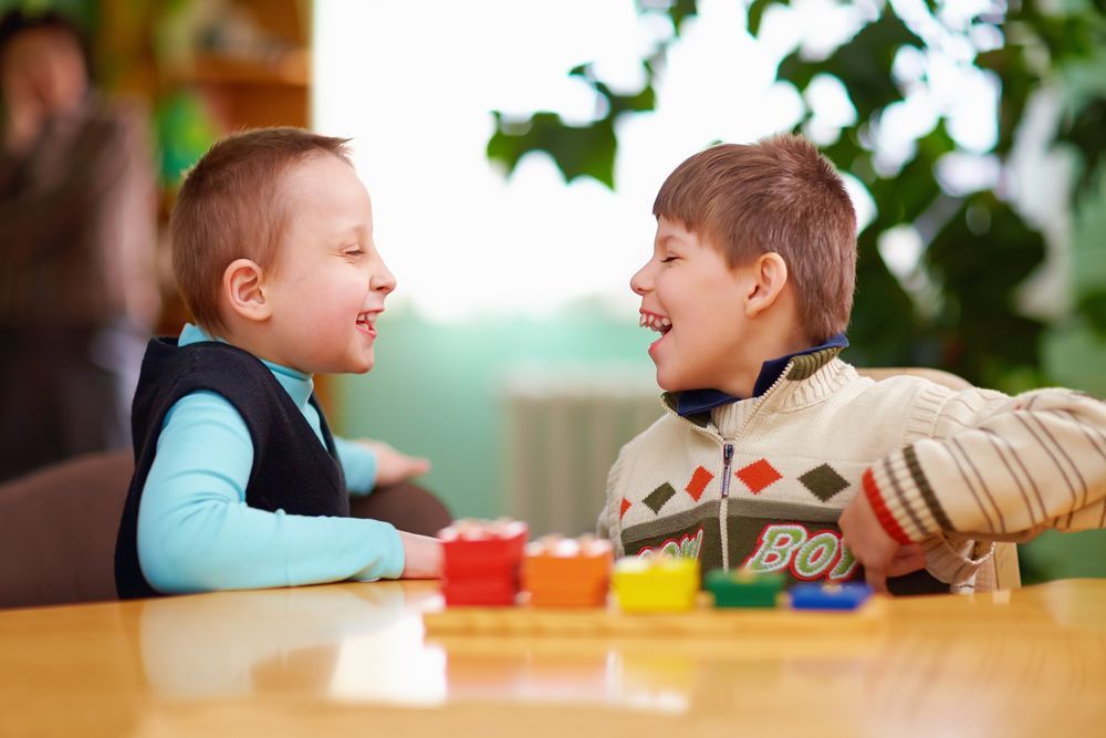 Two Young Boys Are Sitting at a Table Playing With Toys — Specialist Support Solutions in Gladstone, QLD