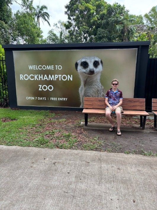 A Man is Sitting on a Bench in Front of a Sign — Specialist Support Solutions in Gladstone, QLD