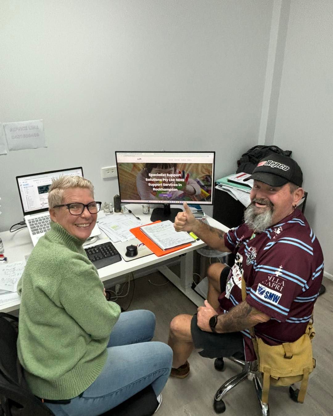 A Man and a Woman Are Sitting at a Desk in Front of a Computer — Specialist Support Solutions in Emerald, QLD