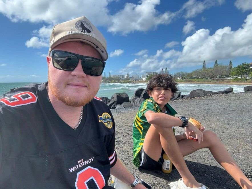 A Man and a Boy Are Sitting on the Beach — Specialist Support Solutions in Yeppoon, QLD