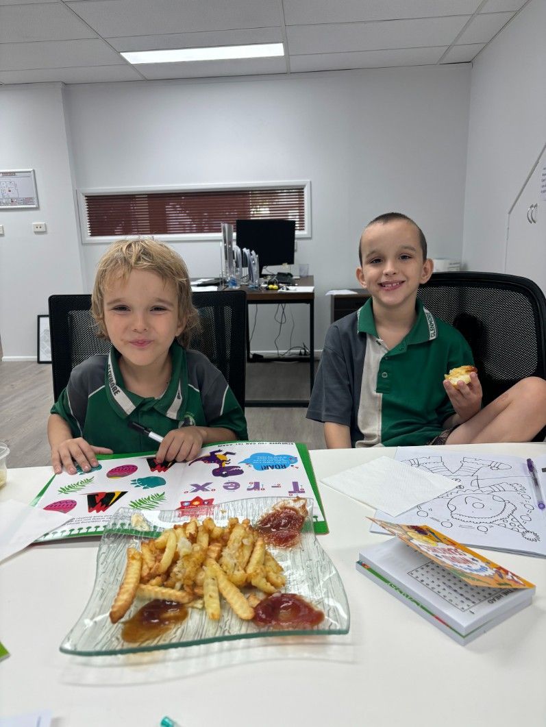 Two Children Are Sitting at a Table With a Plate of French Fries — Specialist Support Solutions in Emerald, QLD