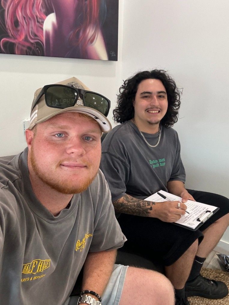 Two Men Are Sitting Next to Each Other in a Waiting Room — Specialist Support Solutions in Emerald, QLD