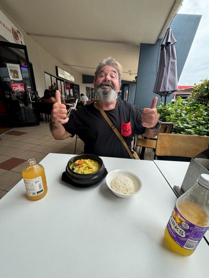 A Man is Sitting at a Table With a Bowl of Food — Specialist Support Solutions in Emerald, QLD