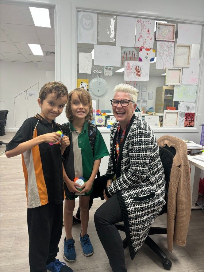 A Woman is Sitting in a Chair With Two Children Standing Next to Her — Specialist Support Solutions in Rockhampton City, QLD