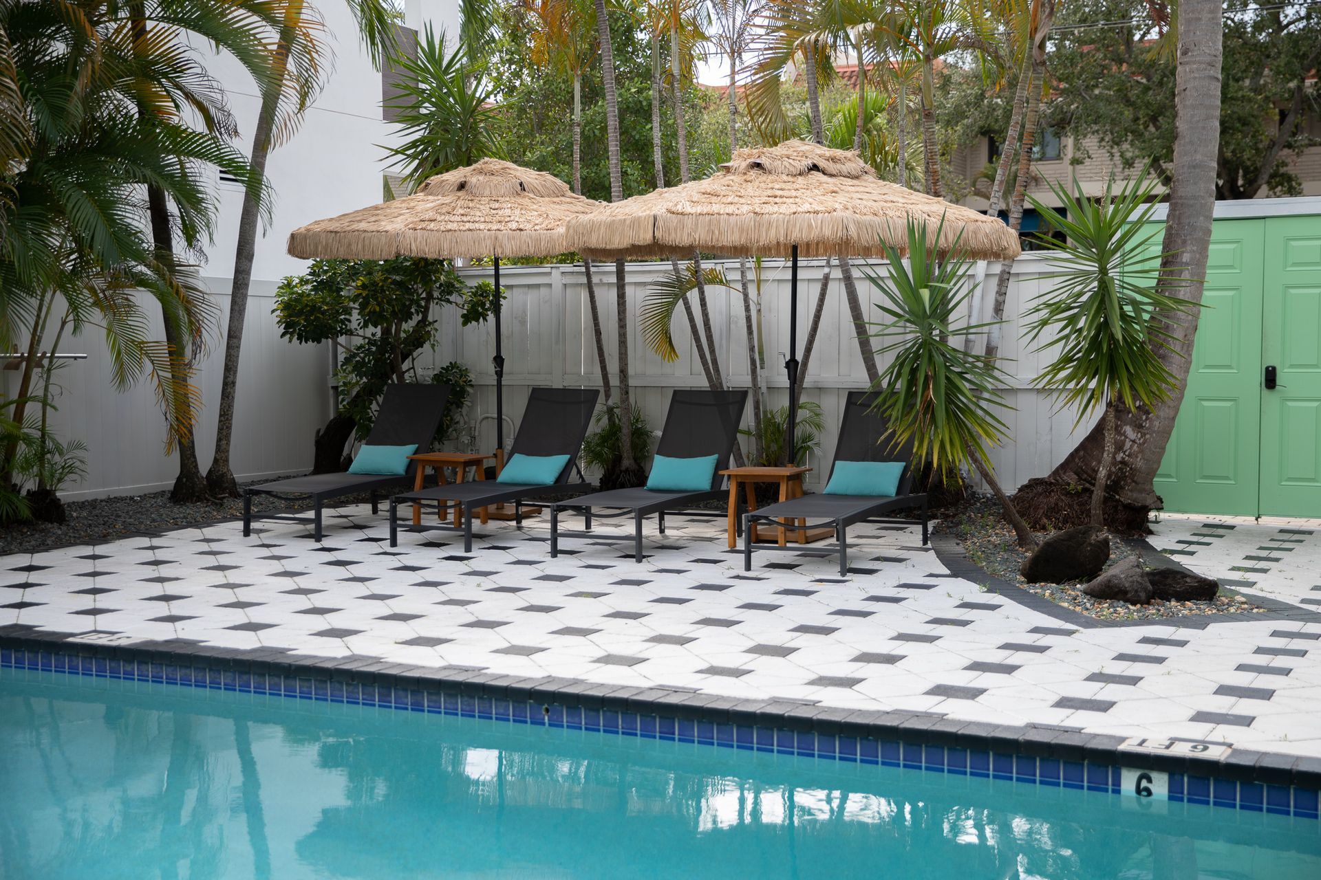 Poolside with lounge chairs under thatched umbrellas.