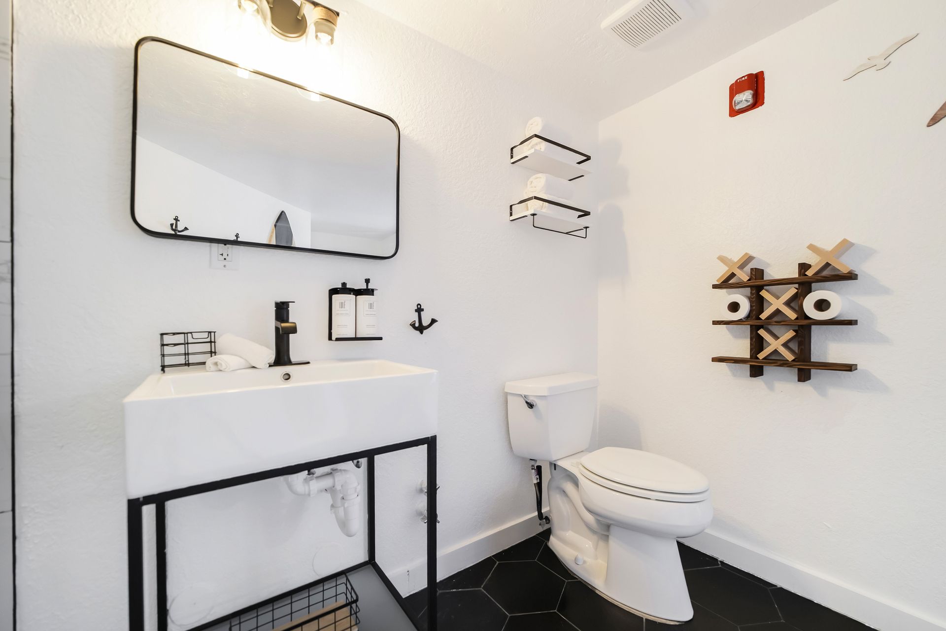 Bathroom with white walls, black accents, and a tic-tac-toe toilet paper holder.