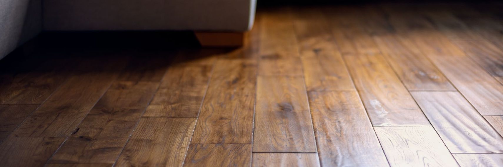 Wooden floor with sunlight and shadows near a dark wall or doorway