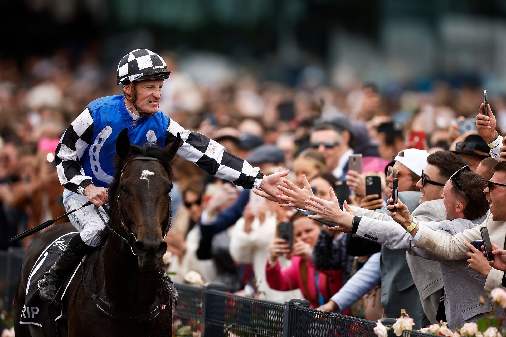 HBA Media | a jockey is riding a horse in front of a crowd of people .