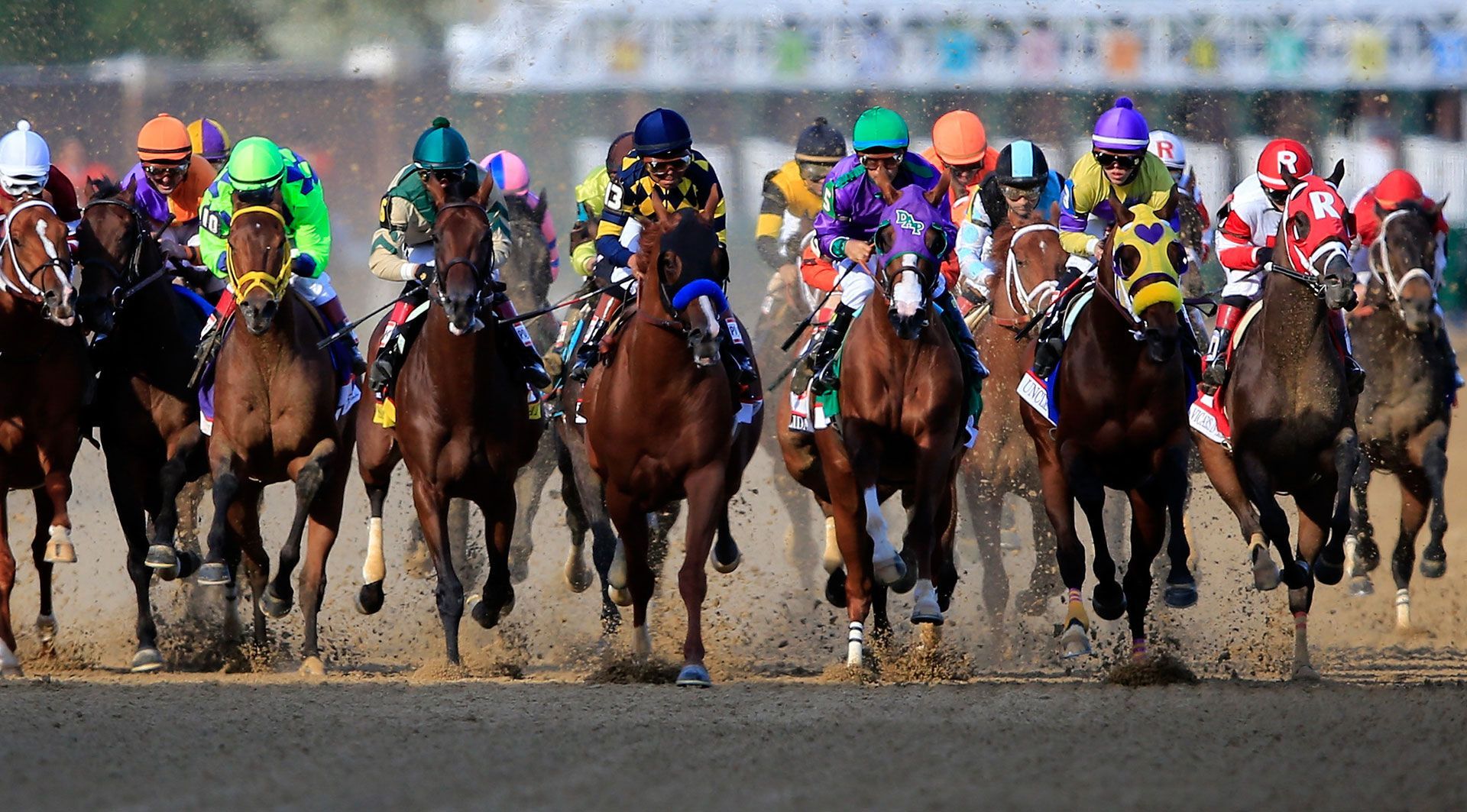 A group of horses and jockeys are racing on a track.