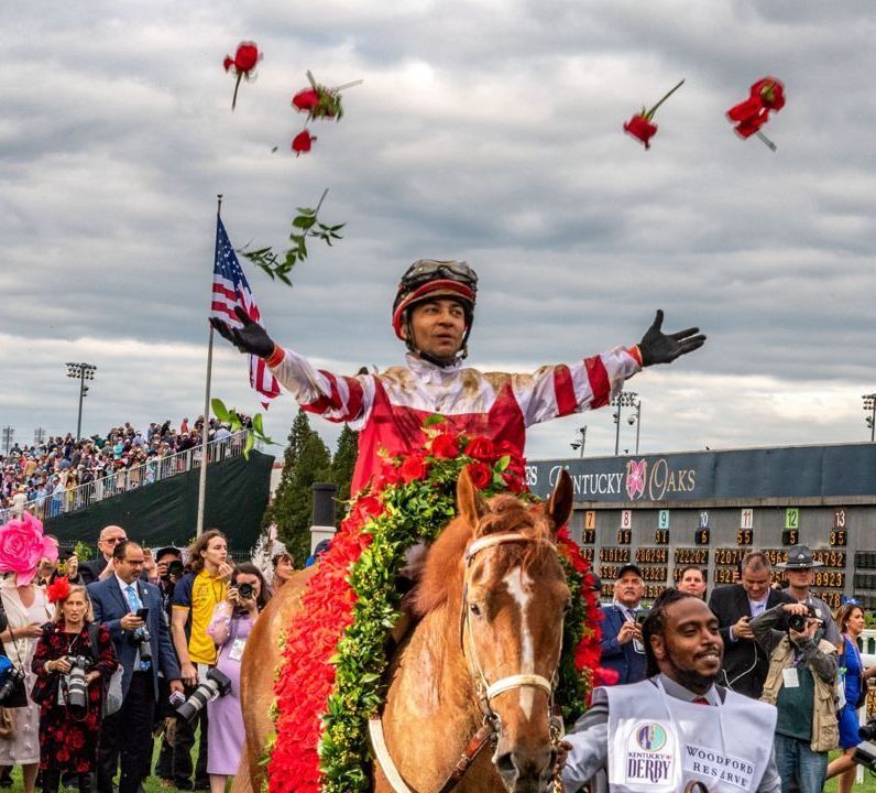 A jockey riding a horse with roses being thrown in the air