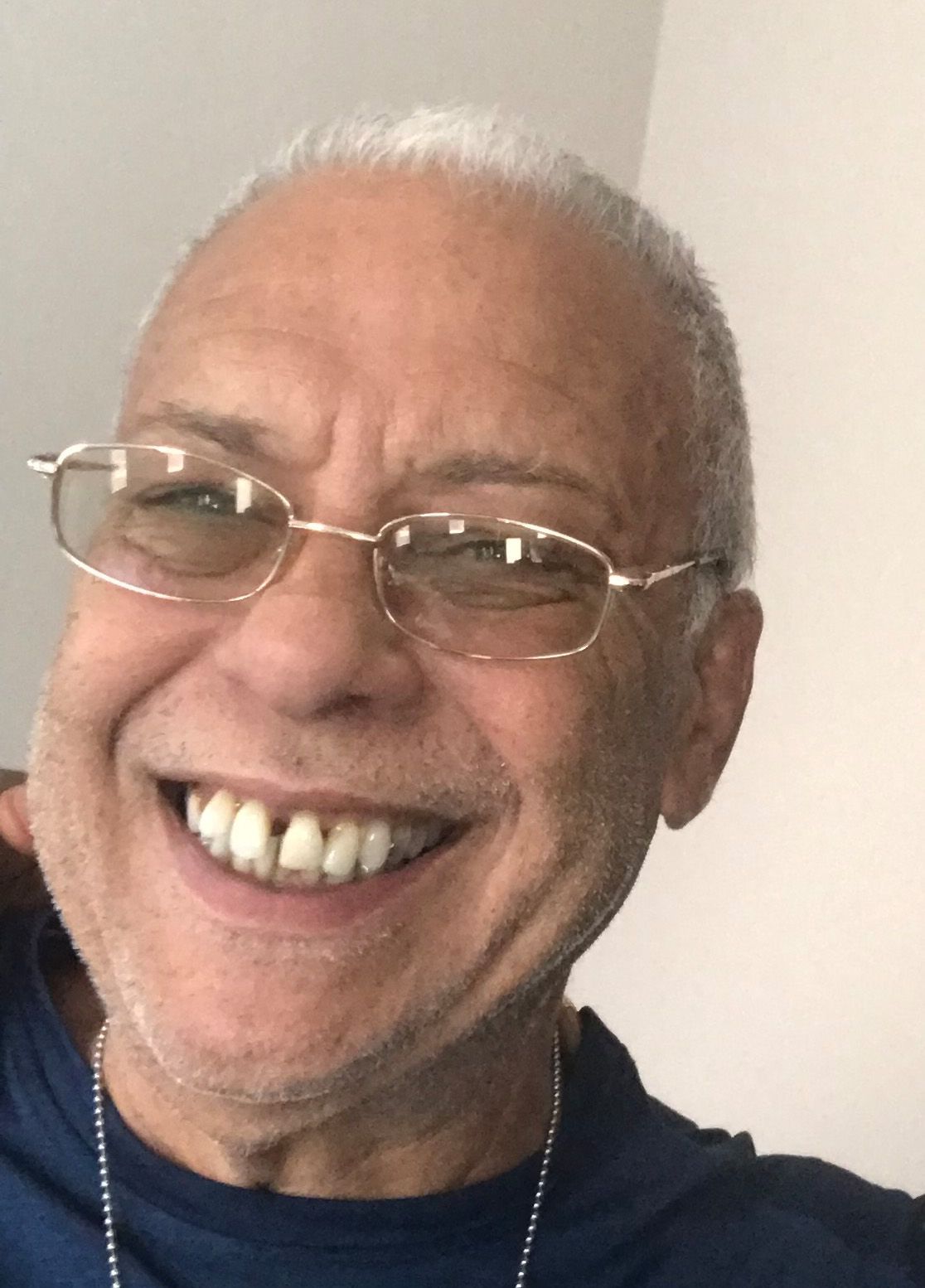 Man with glasses smiles, looking directly at the camera.