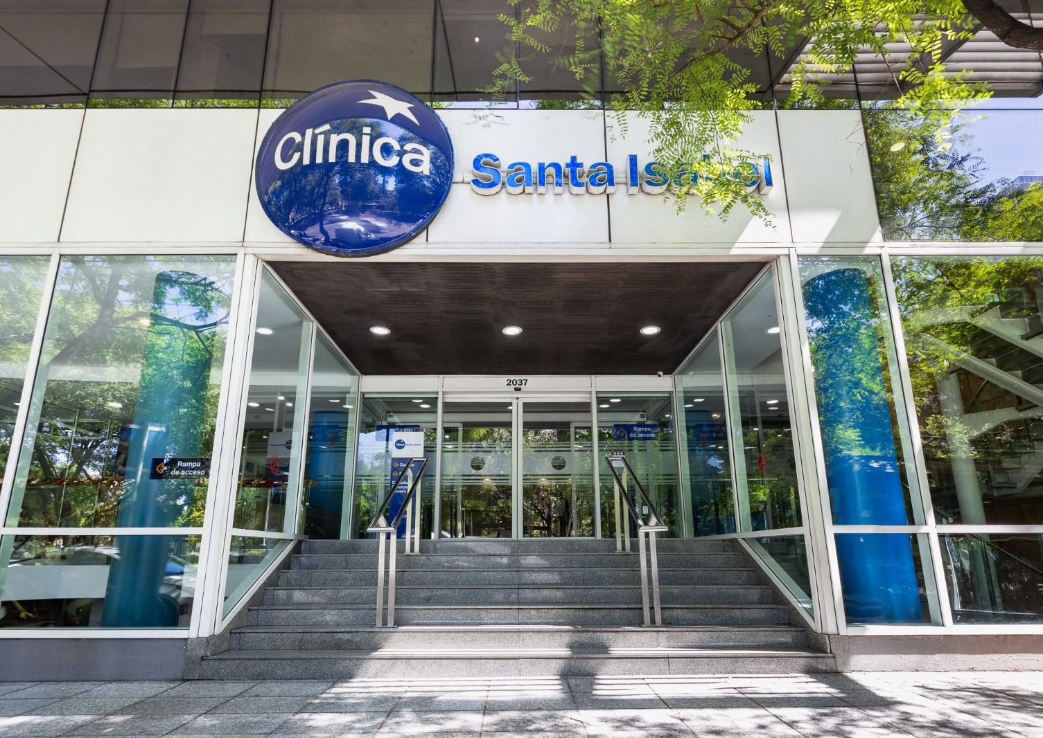 Entrada Clínica Santa Isabel con cartel azul y puertas de cristal.