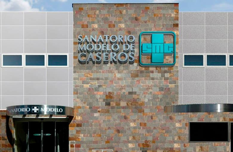 Entrada al edificio Sanatorio Modelo de Caseros con logo verde azulado y fachada de piedra.