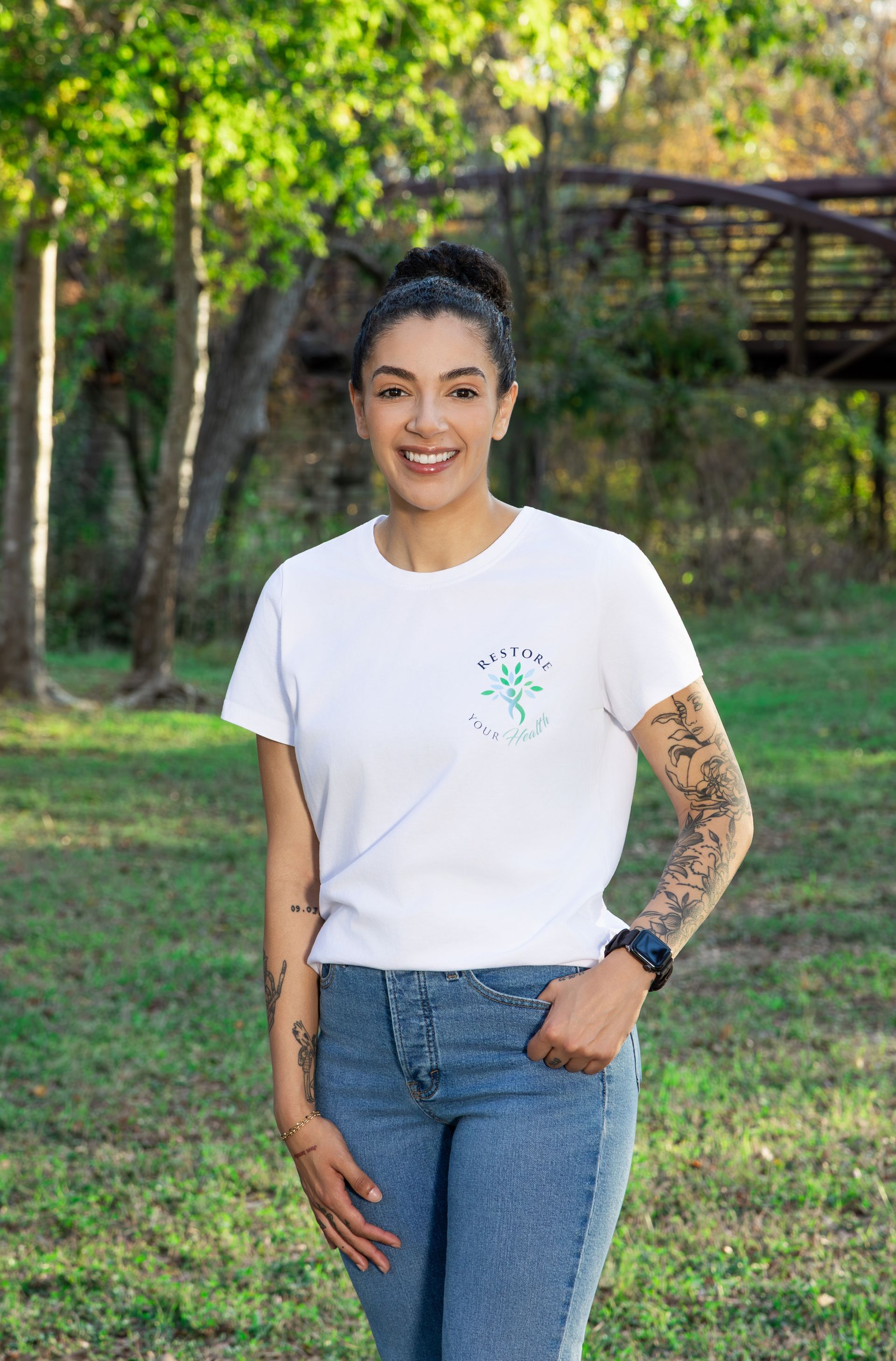 Woman in white shirt and jeans smiling outdoors in autumn.