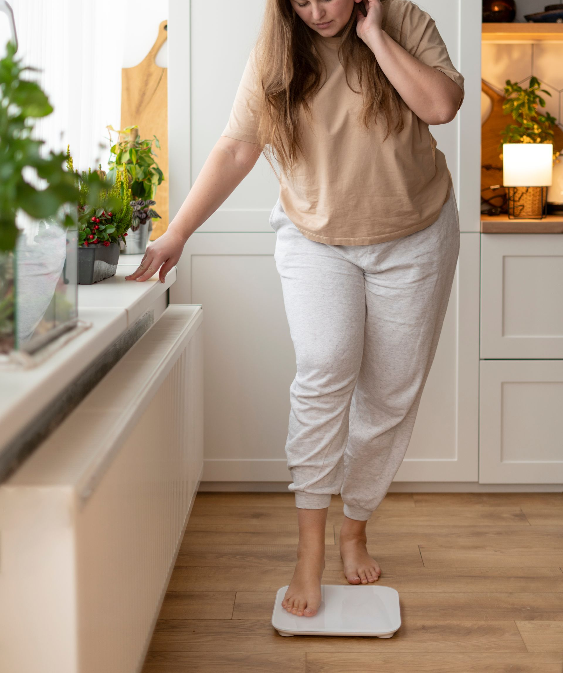 Woman in black bra and pants measuring waist with a white tape measure.