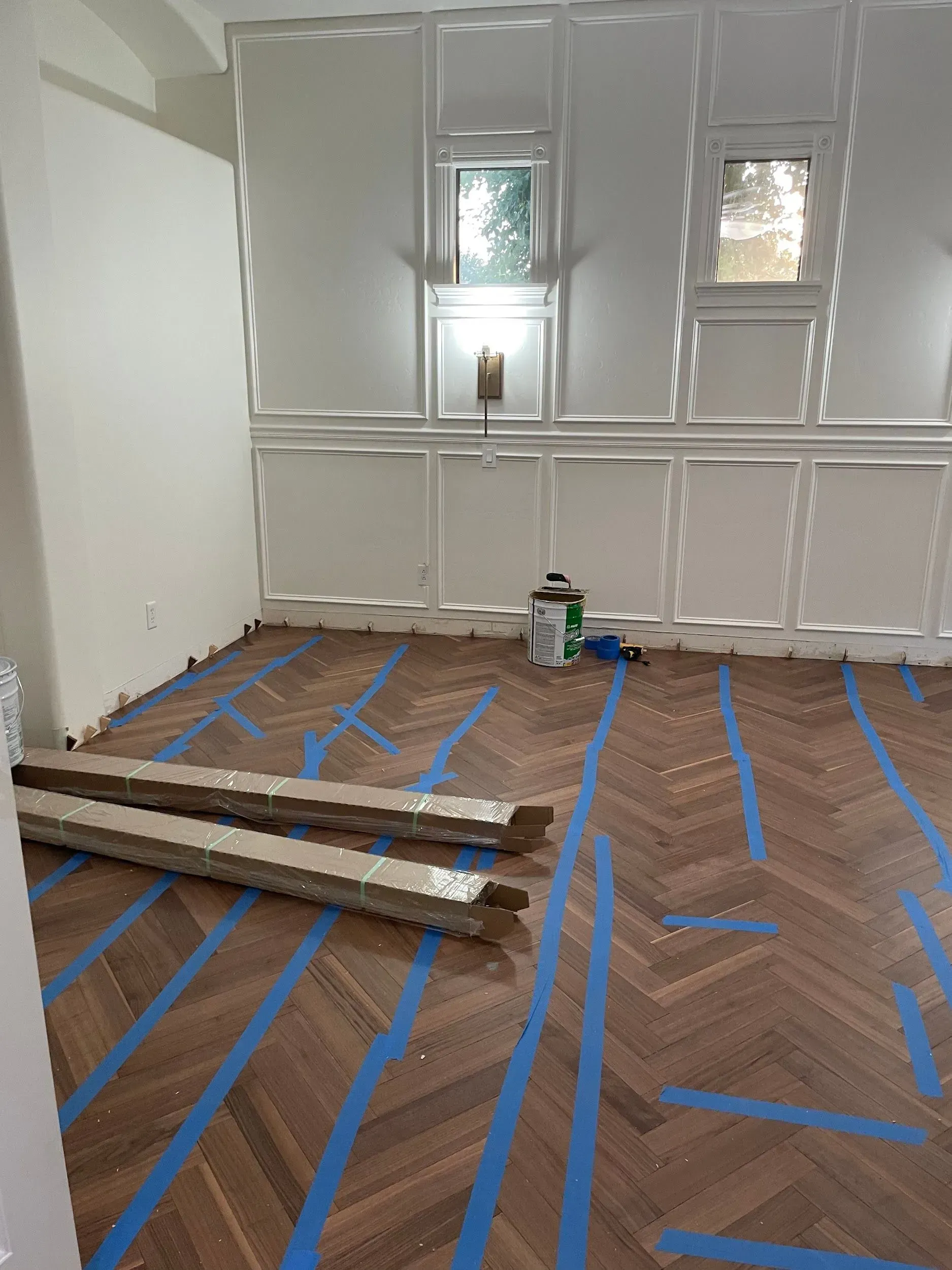A room with a wooden floor and blue tape on it.