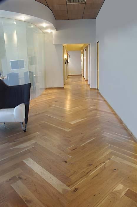 A long hallway with a wooden floor and a chair.