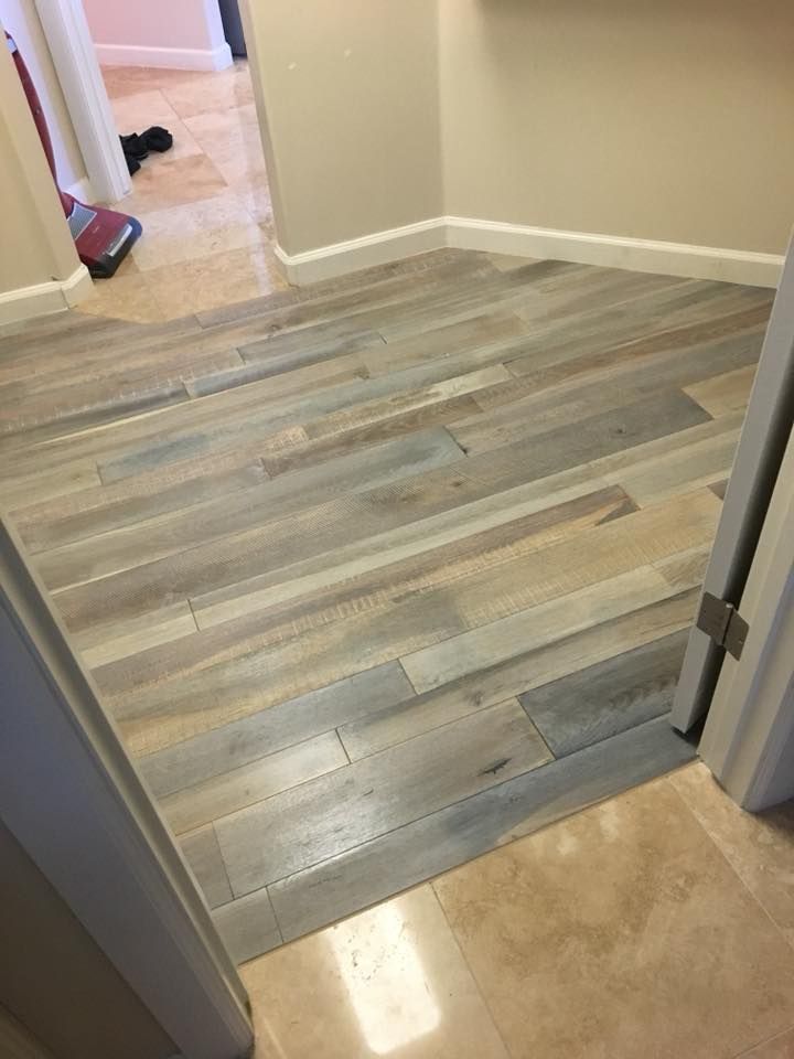 A wooden floor in a hallway next to a door.