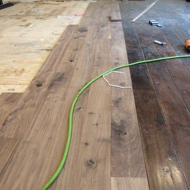 Wood flooring installation in progress, with planks laid over subfloor and a green hose across the floor.