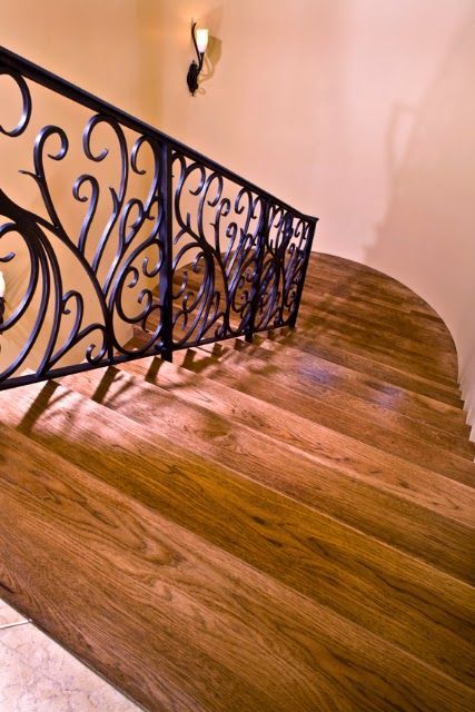 A wooden staircase with a wrought iron railing