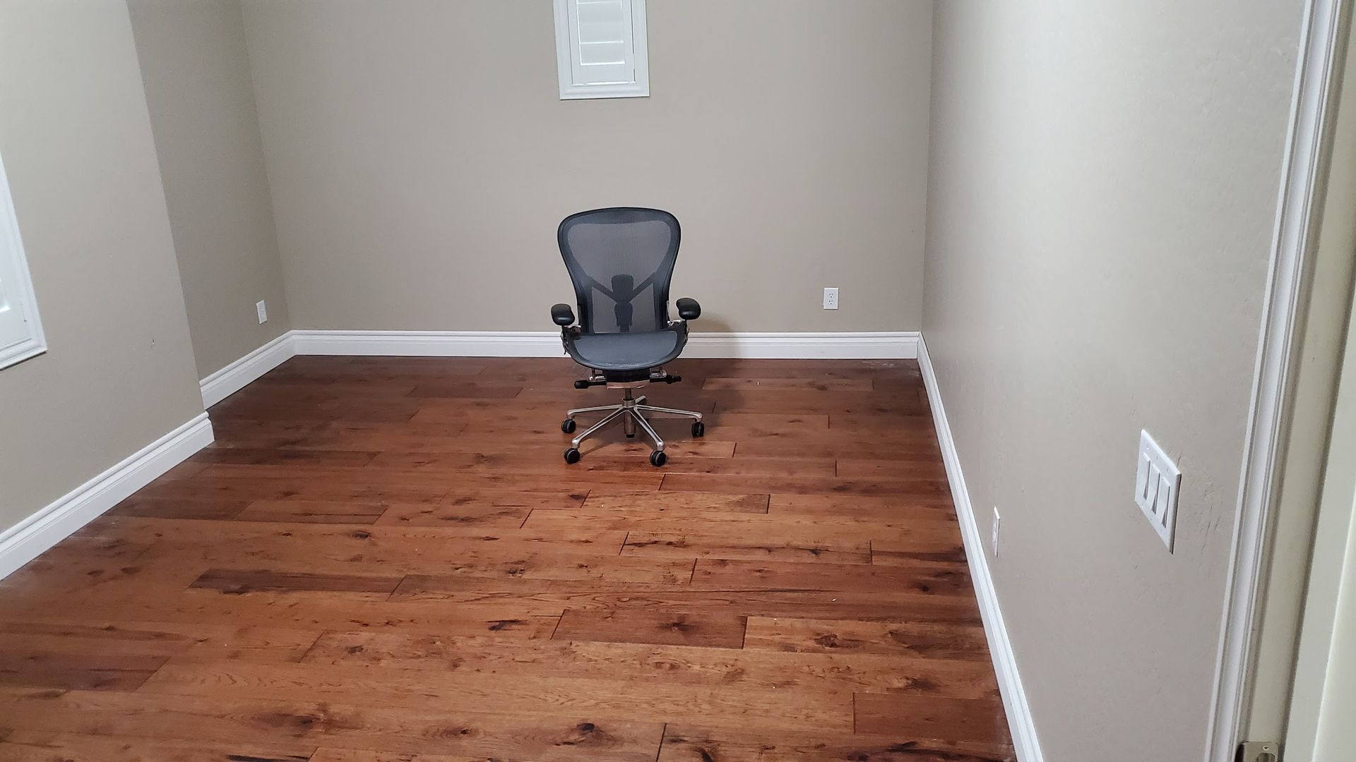 A chair is sitting in the middle of a room with hardwood floors.