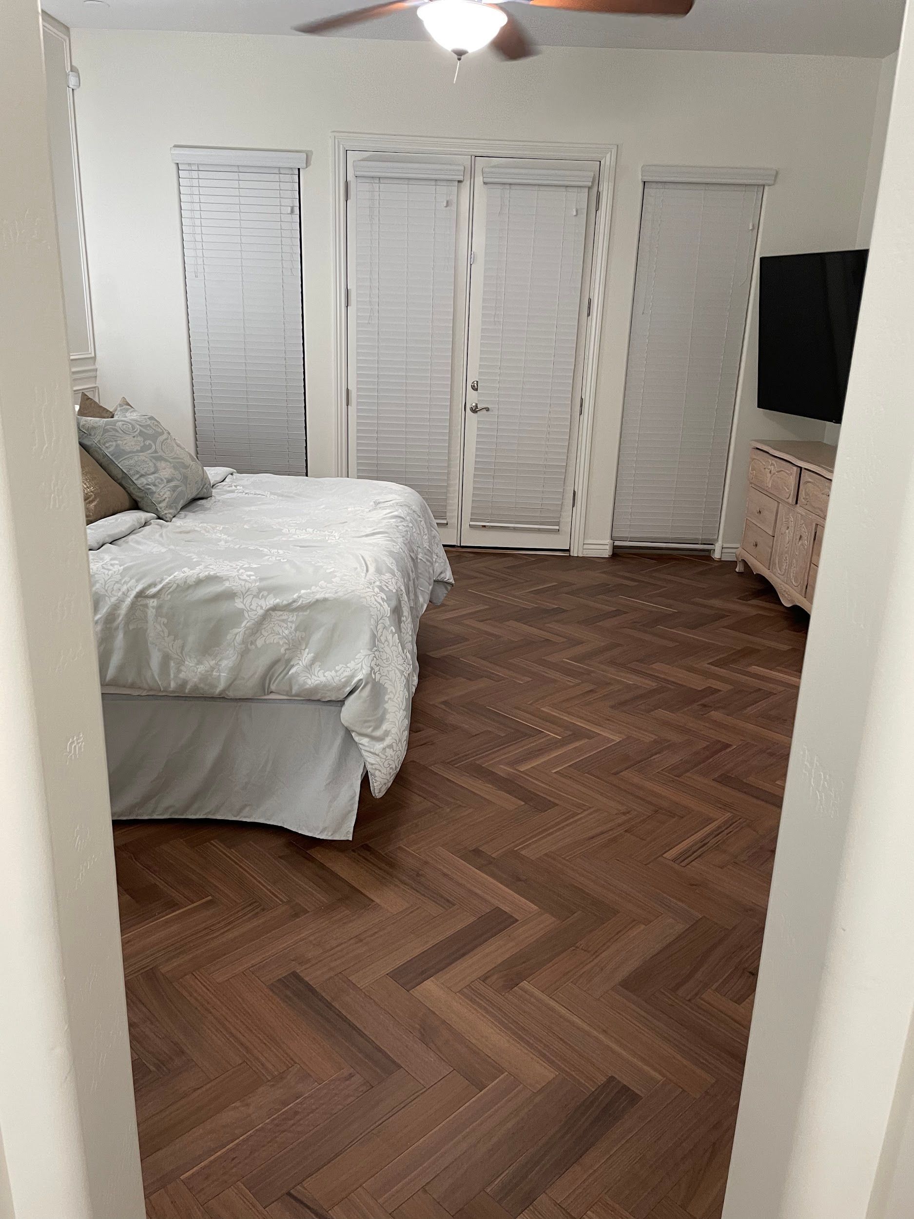 A bedroom with a herringbone floor and a bed.