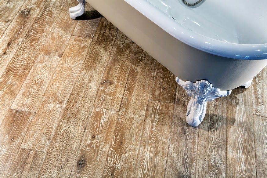 A bathtub is sitting on a wooden floor in a bathroom.