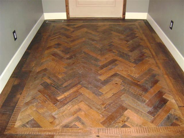 A wooden floor with a herringbone pattern in a hallway.