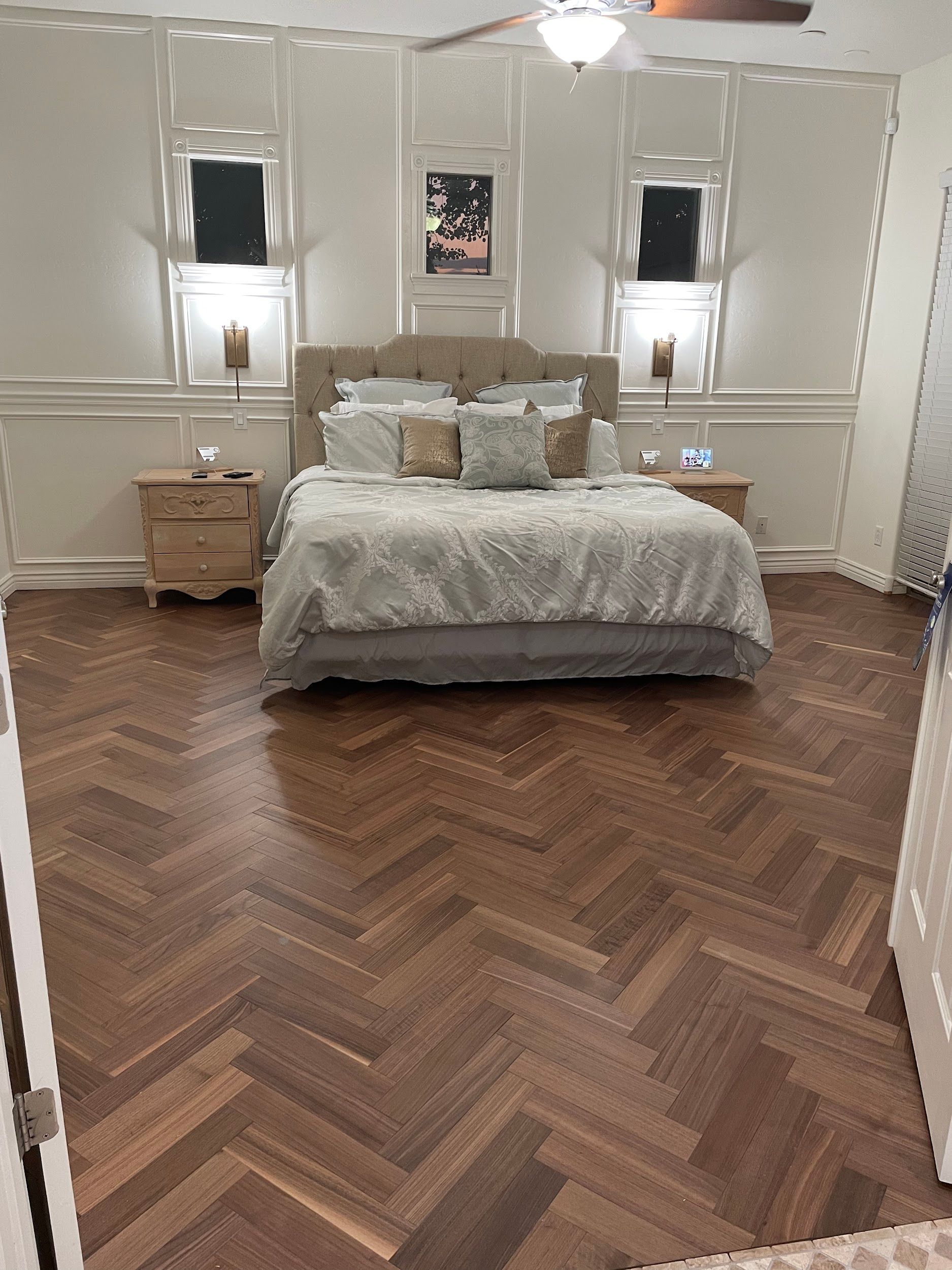 A bedroom with a herringbone floor and a bed.