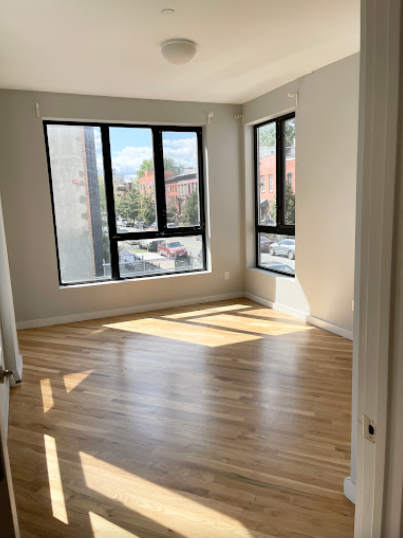 An empty room with hardwood floors and two windows.