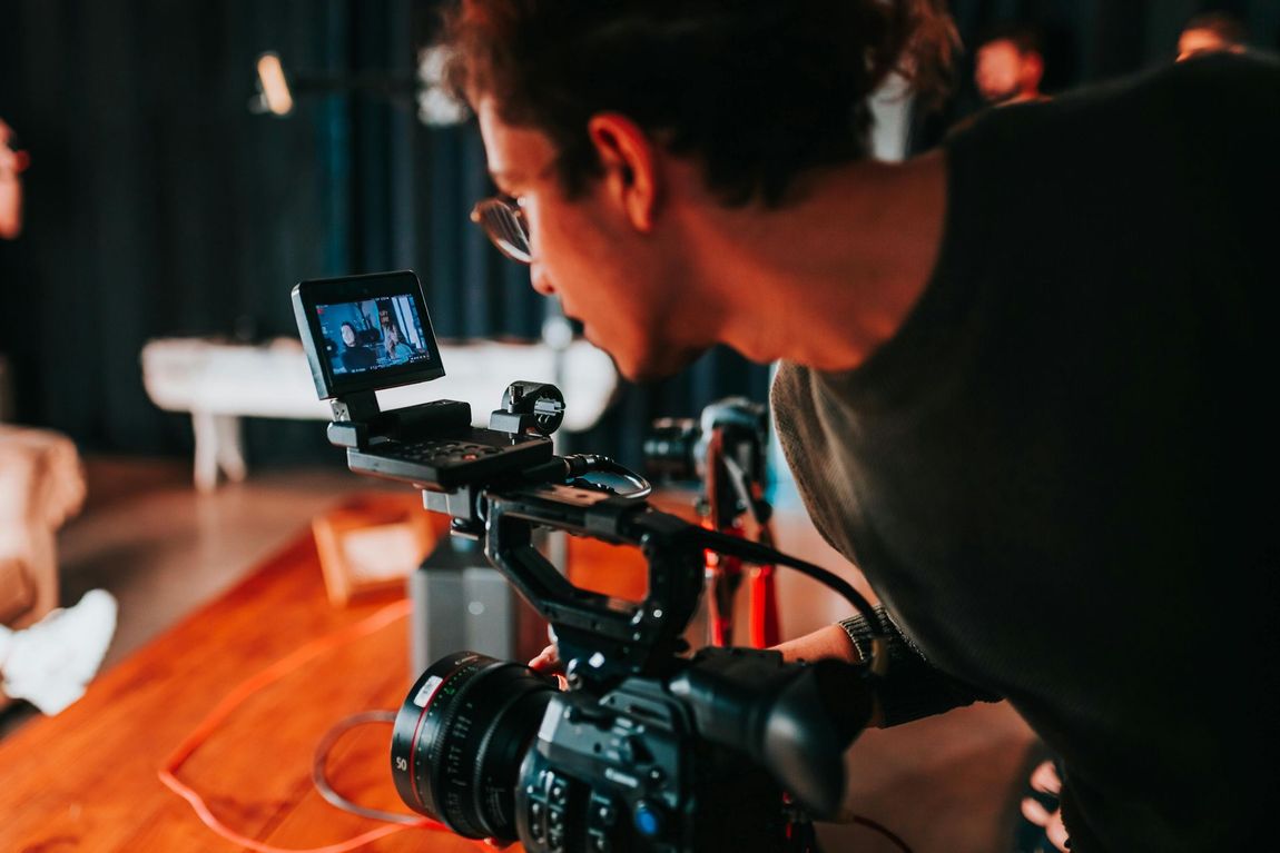 Filmmaker on set standing behind a camera filming a commercial