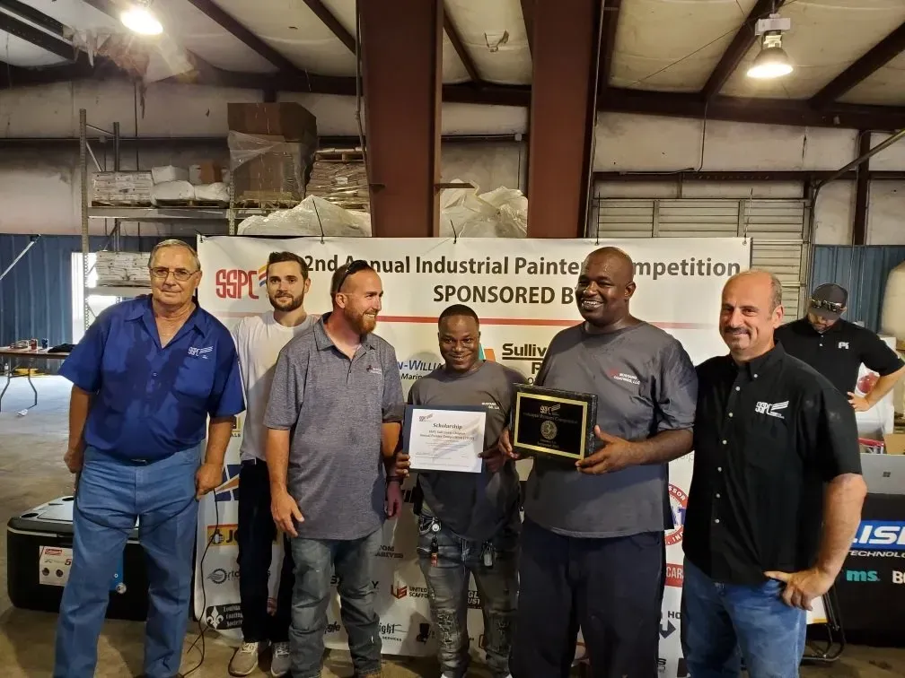 A group of men are posing for a picture in a warehouse.