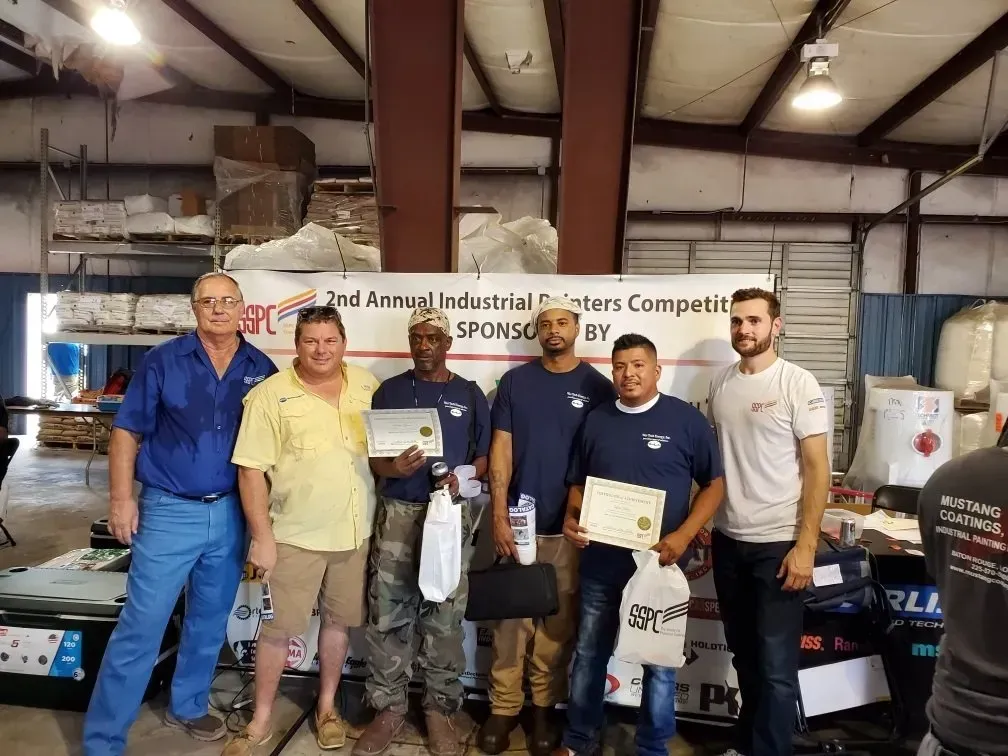 A group of men are posing for a picture in a factory.