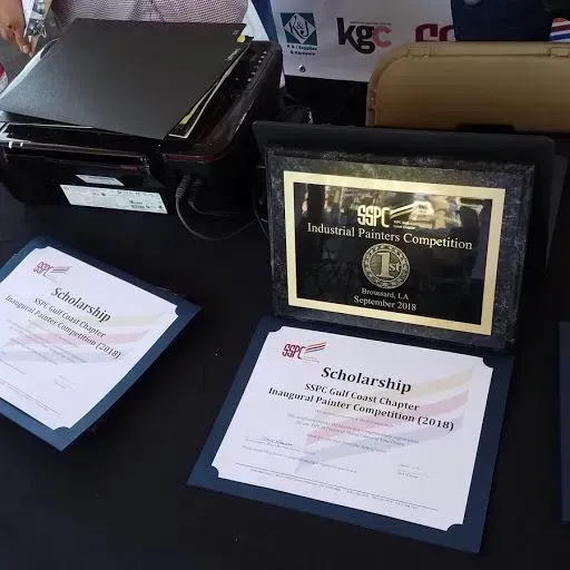 A scholarship certificate sits on a table next to a plaque