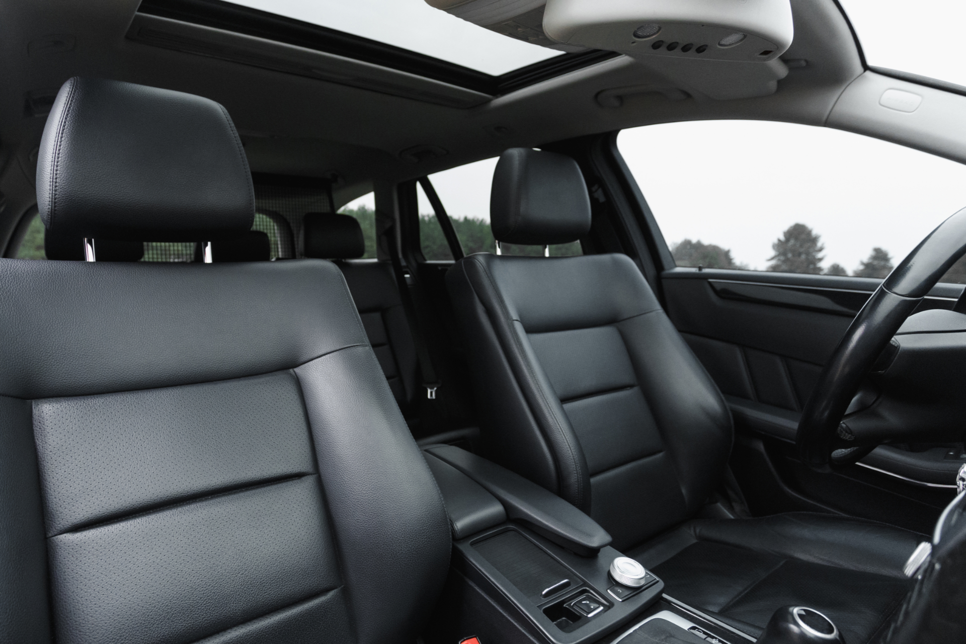 Black leather car interior with front seats, steering wheel, and sunroof.