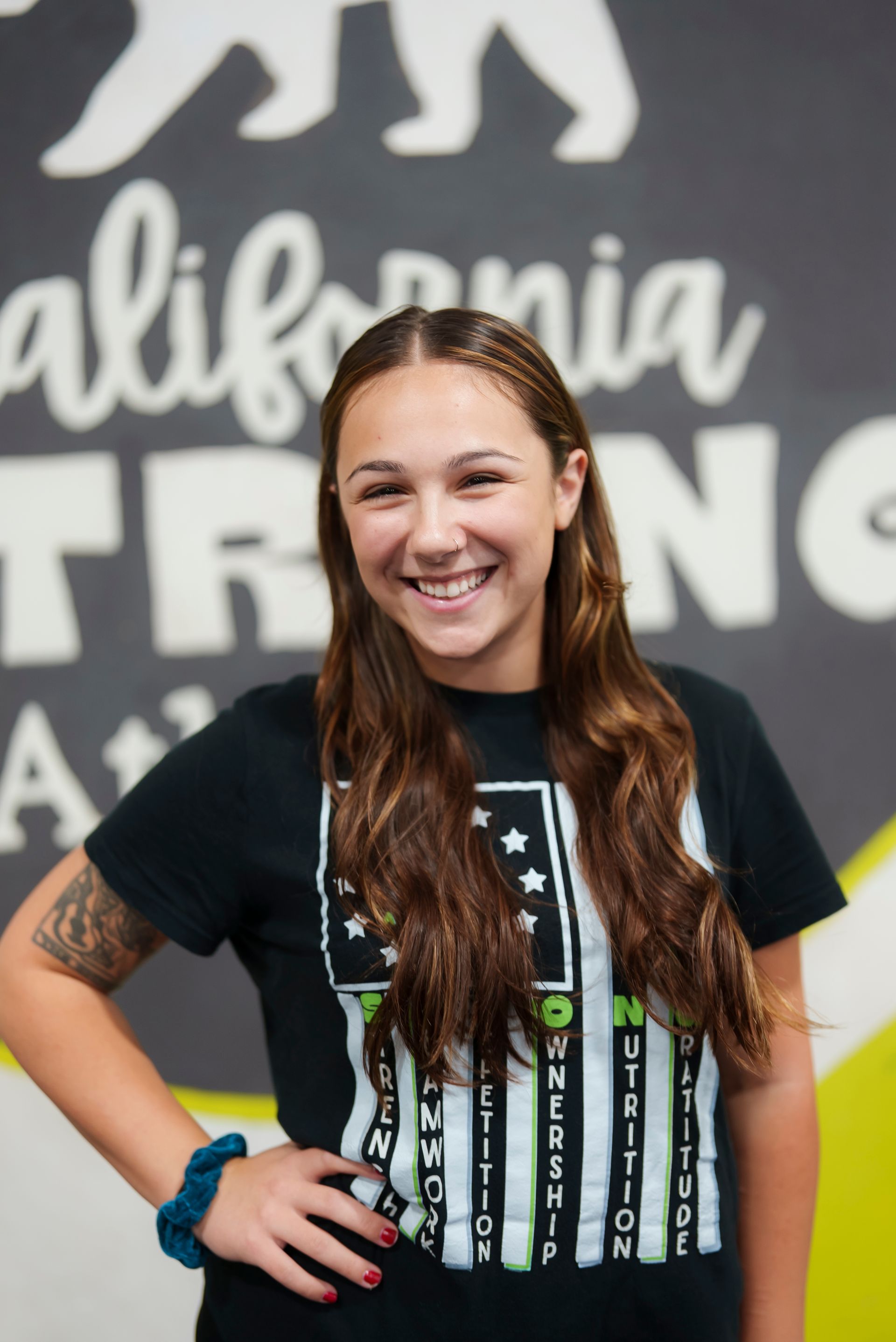 Smiling woman with arm tattoo, in front of a 