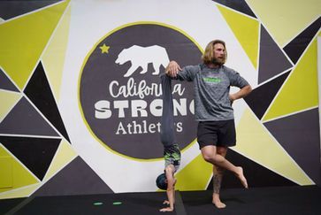 A little girl is doing a split on a blue mat