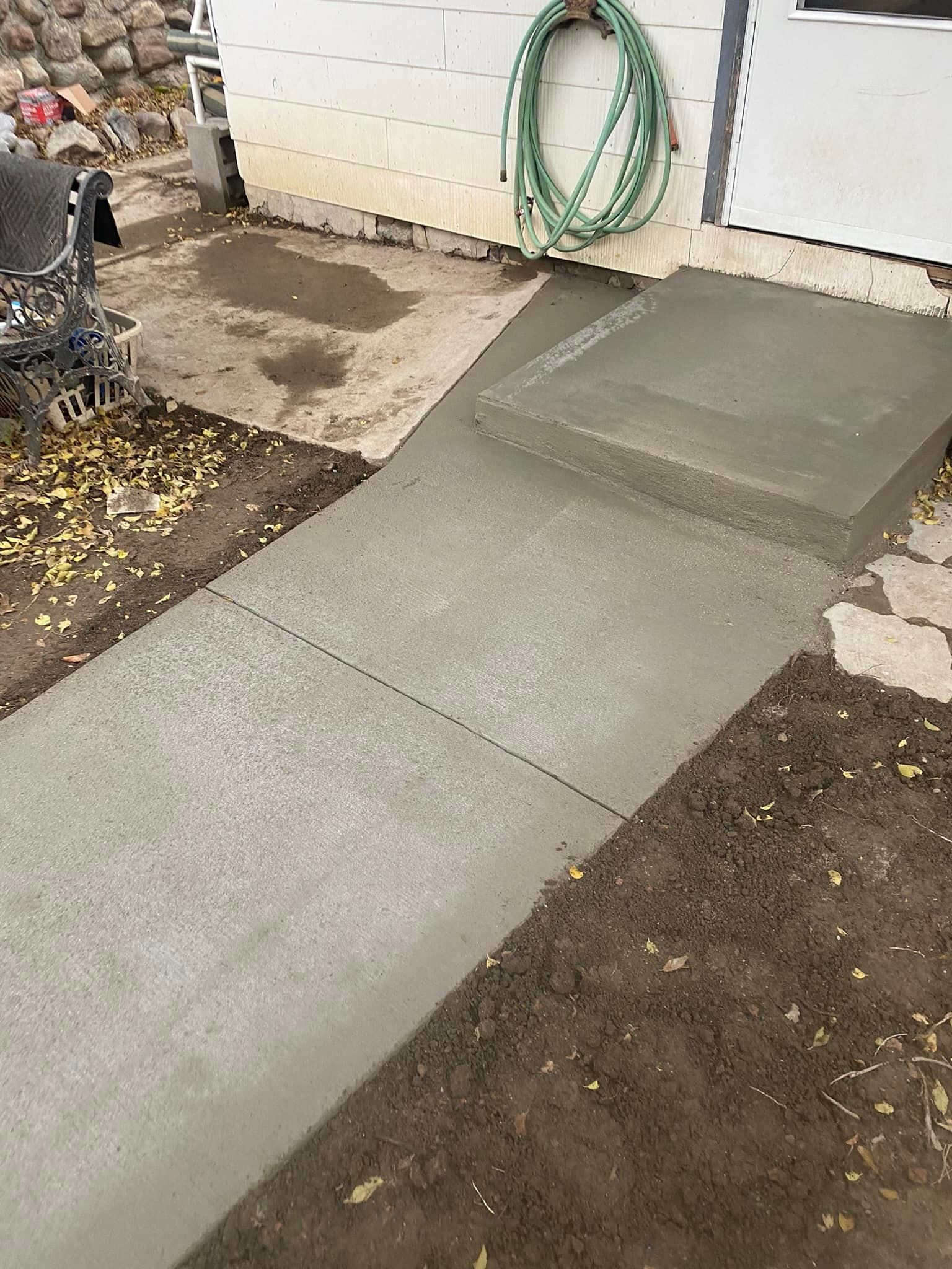 A concrete walkway is being built in front of a house.
