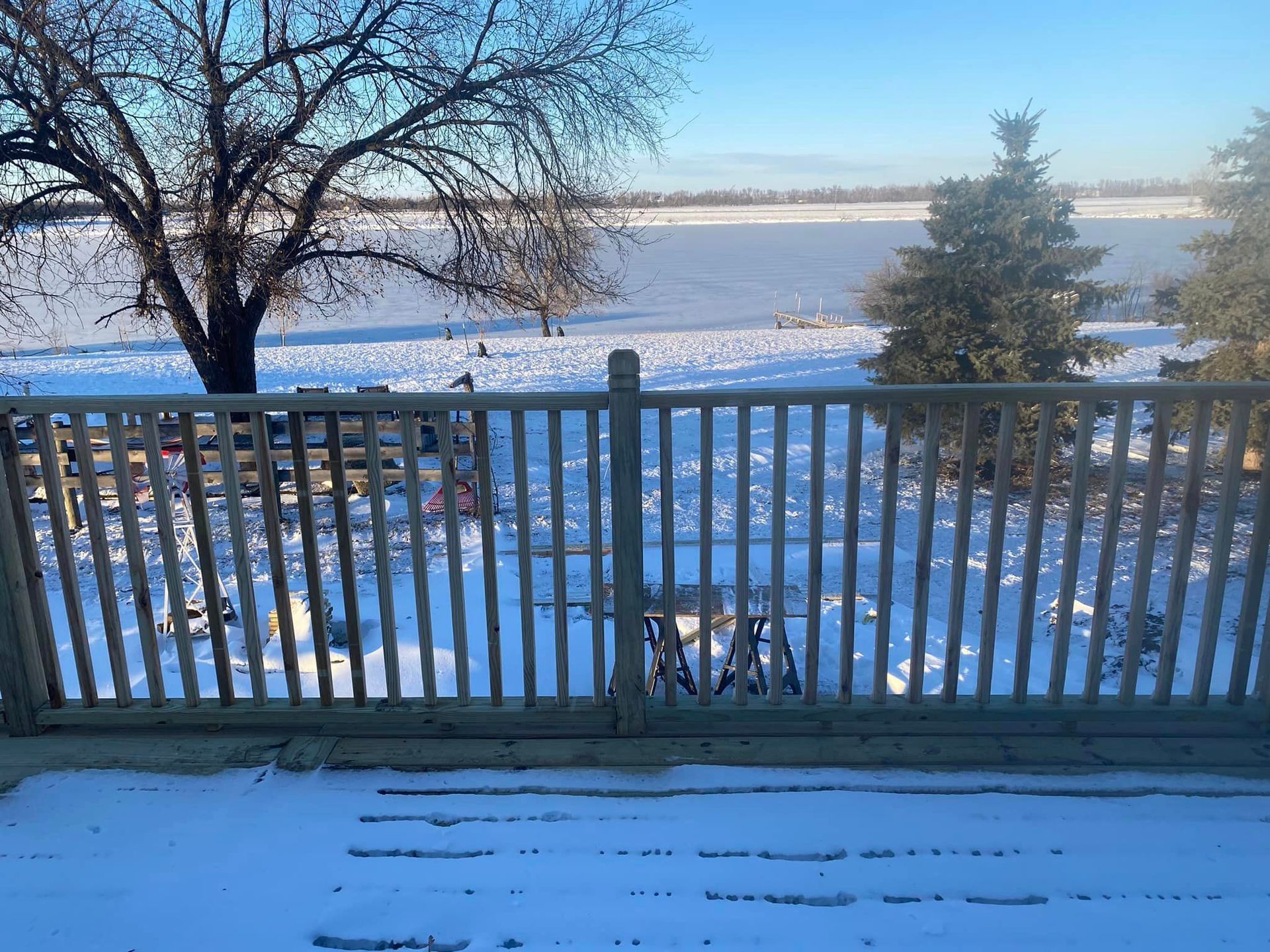 A wooden fence with a view of a snowy field behind it.
