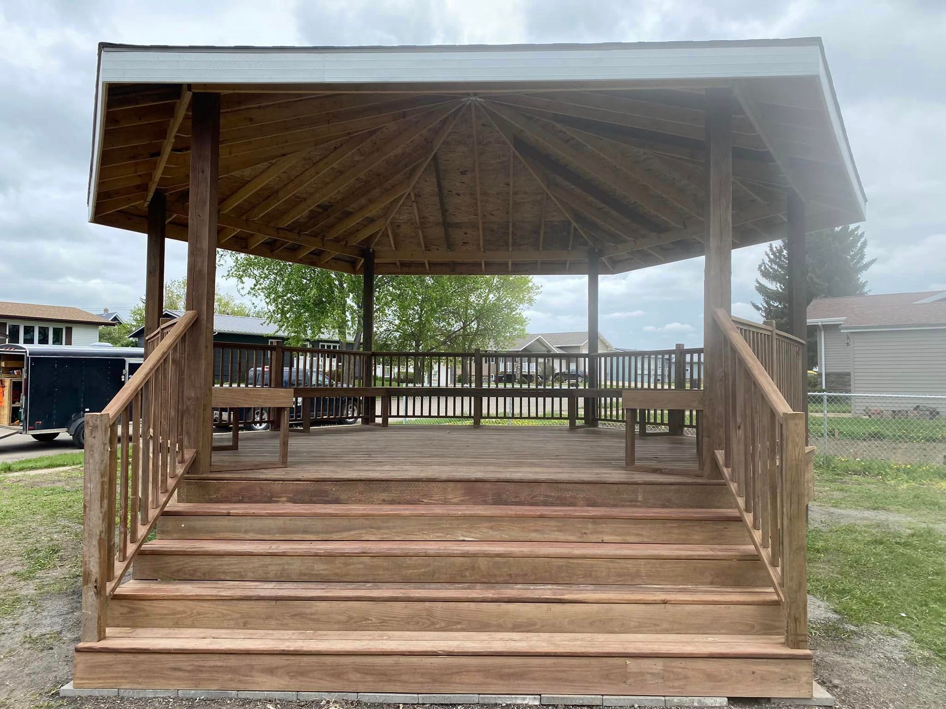 A wooden gazebo with stairs leading up to it.