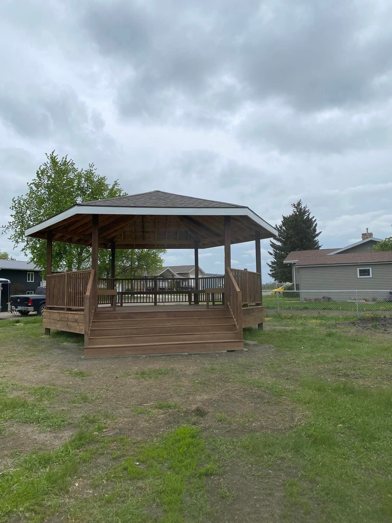 A gazebo is sitting in the middle of a grassy field.