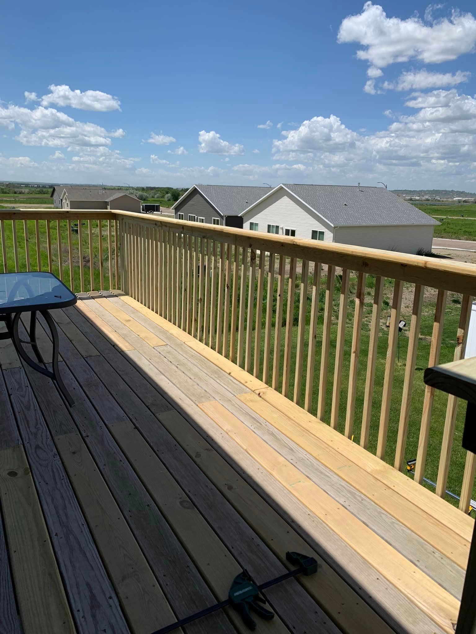 A wooden deck with a table and chairs and a view of a residential area.